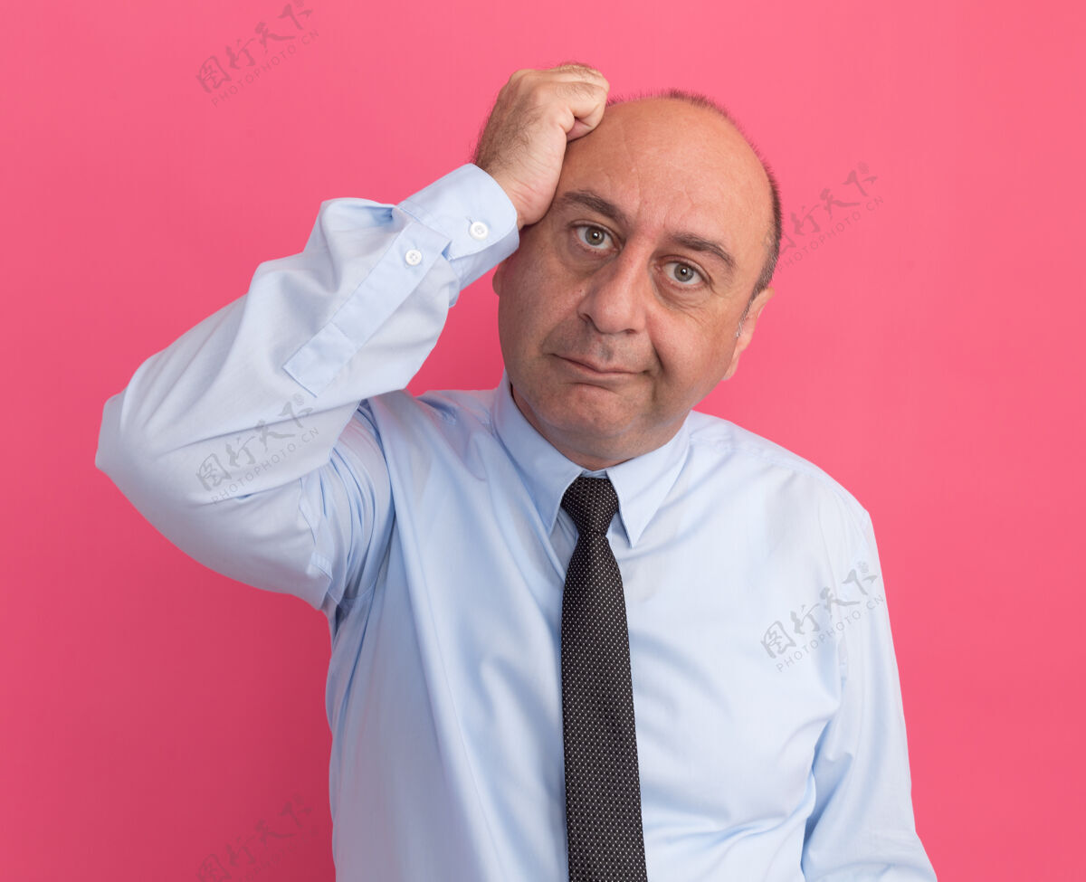 人高兴的歪着头的中年男子穿着白色t恤 打着领带 手放在头上 隔离在粉红色的墙上人人倾斜