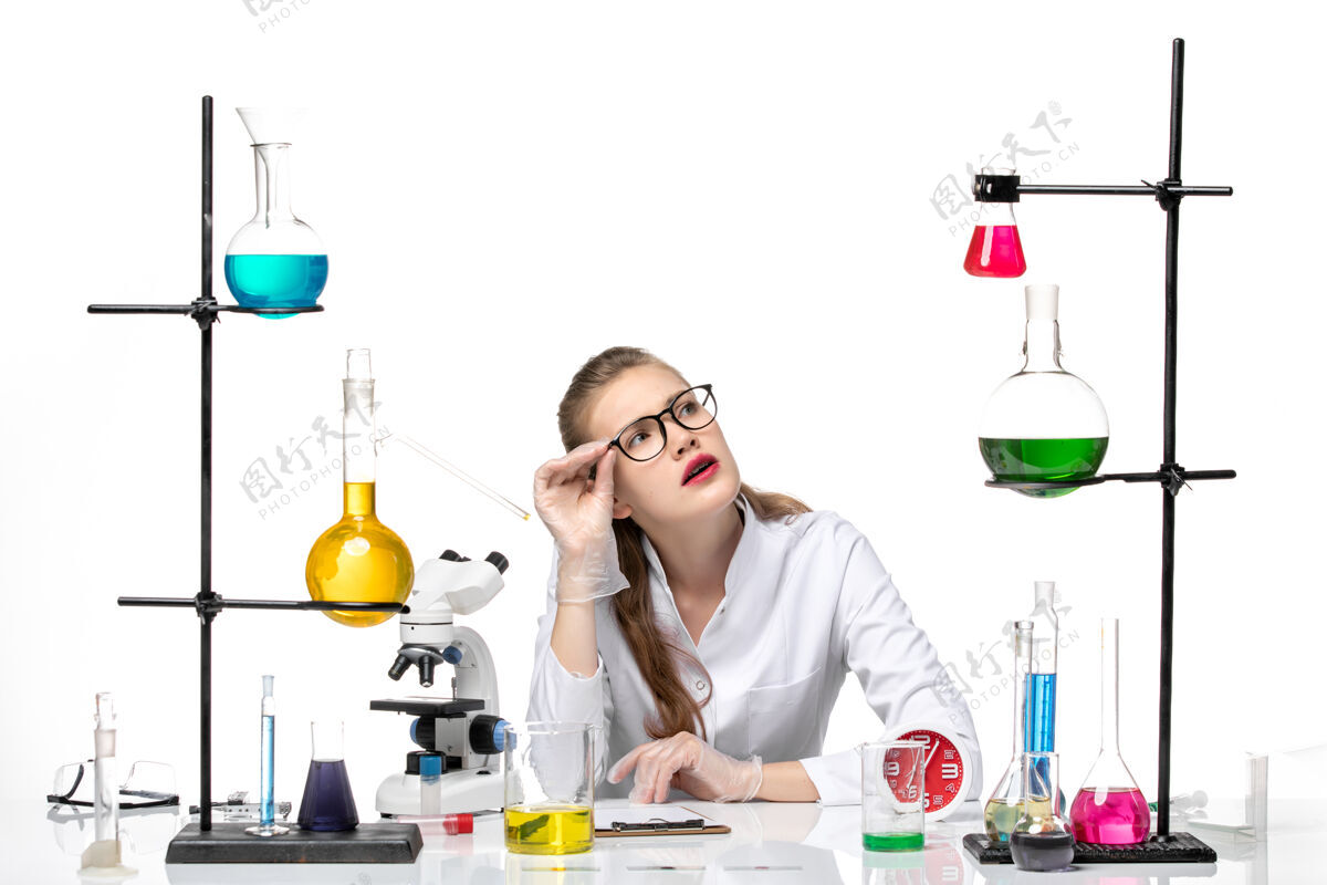 化学前视图穿着白色医疗服的女医生坐在桌子前 用白色背景上的解决方案病毒健康冠状病毒大流行化学坐视野医生