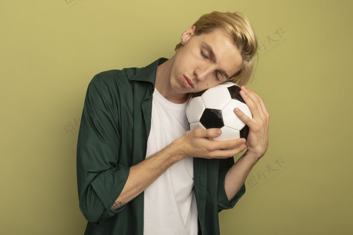 人年轻的金发男人闭着眼睛 穿着绿色t恤 脸上拿着球眼睛年轻脸颊