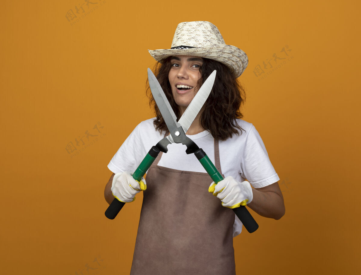 年轻人年轻的女园丁面带微笑 穿着制服 戴着园艺帽和手套 手里拿着剪刀微笑人剪子