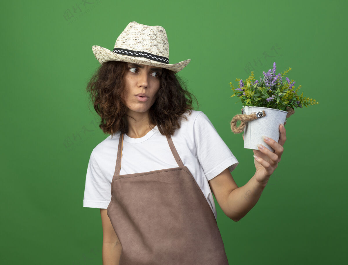 印象穿着制服的年轻女园丁戴着园艺帽 手持花盆 看着花儿 给人留下了深刻的印象帽子花盆花