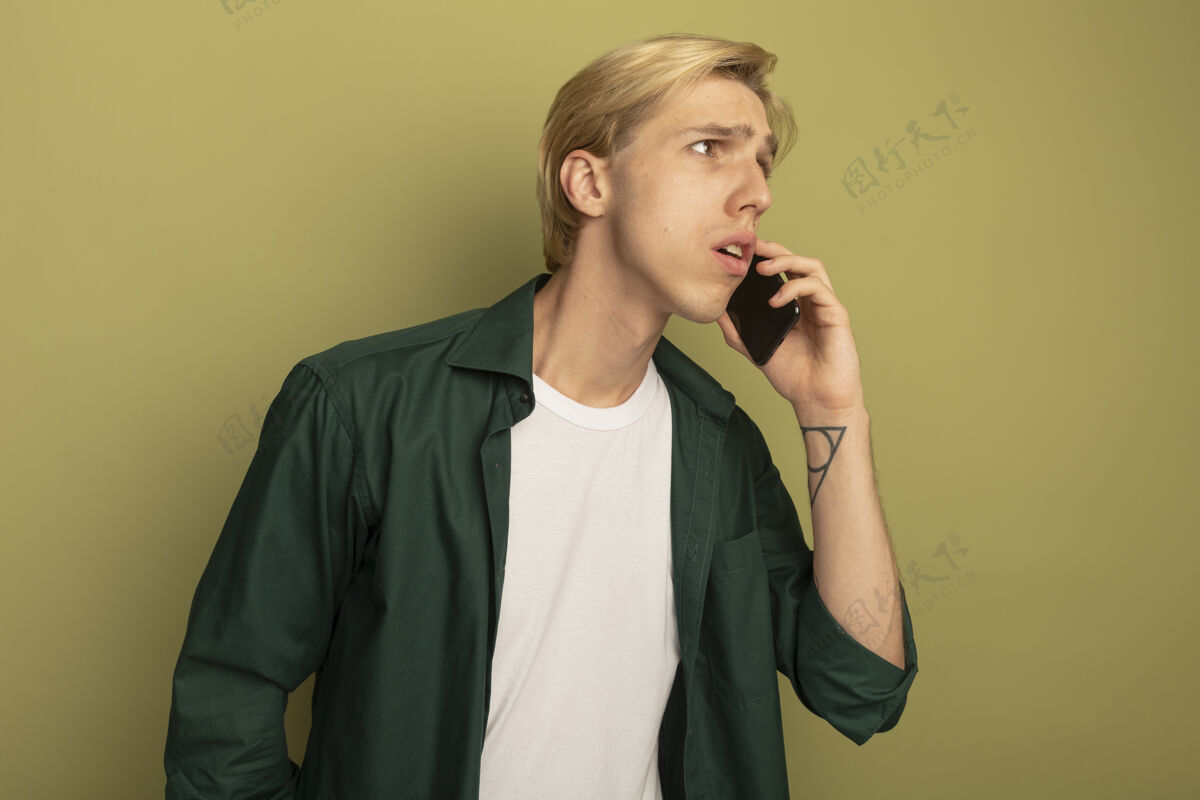 男人困惑地看着身边穿着绿色t恤的金发小伙子在打电话侧身电话帅哥