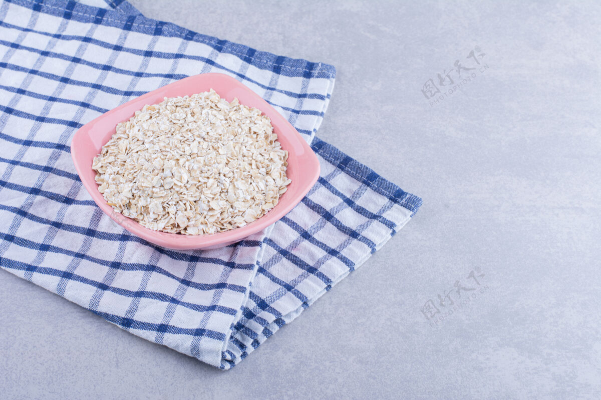 粮食粉红色的碗放在毛巾上 装满燕麦片 放在大理石表面碗健康燕麦片