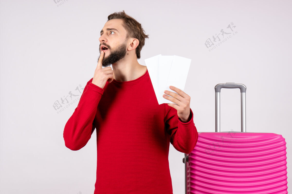风景正面图年轻男子手持粉色包和飞机票上白墙航班旅行度假情感照片游客游客航班度假