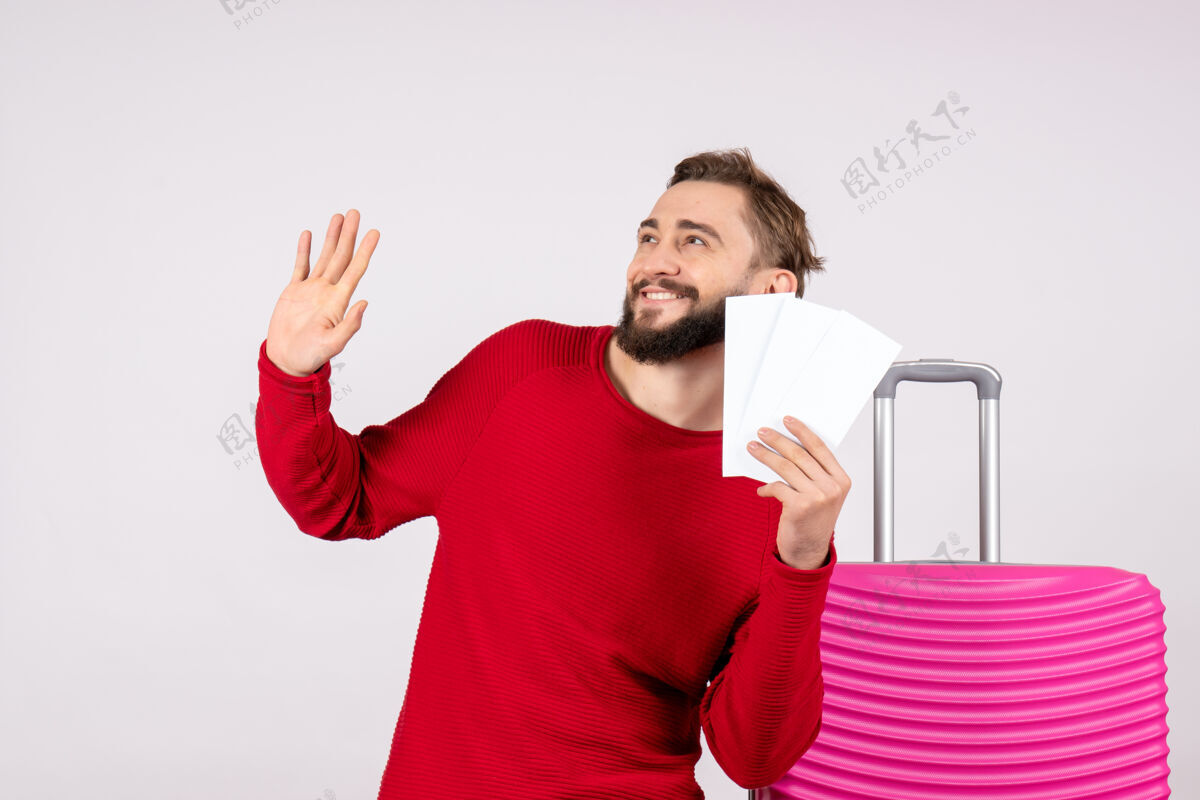 情感正面图年轻男子手持粉色包 手持飞机票上白墙航程飞行度假情感照片游客度假成人男人