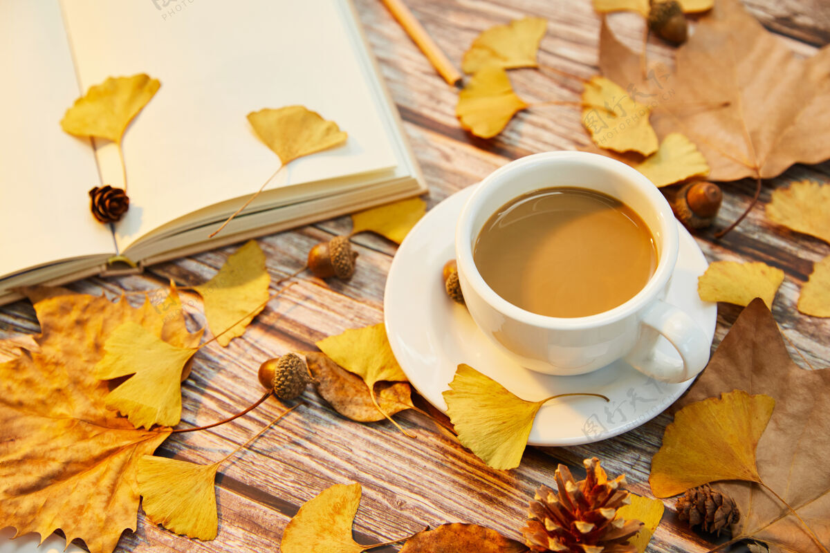 杯子一杯咖啡和秋叶在木头表面的特写镜头质地秋天明亮的
