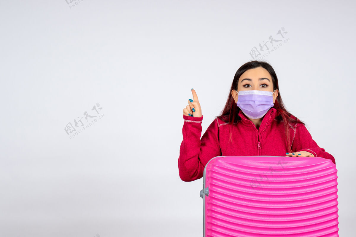 病毒正面图：年轻女性戴着粉色袋子 戴着白墙面具 病毒女性covid-彩色旅行大流行女人漂亮颜色