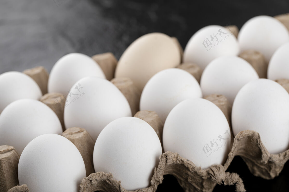 鸡蛋在黑色的表面装白色鸡蛋的容器纸箱容器食物