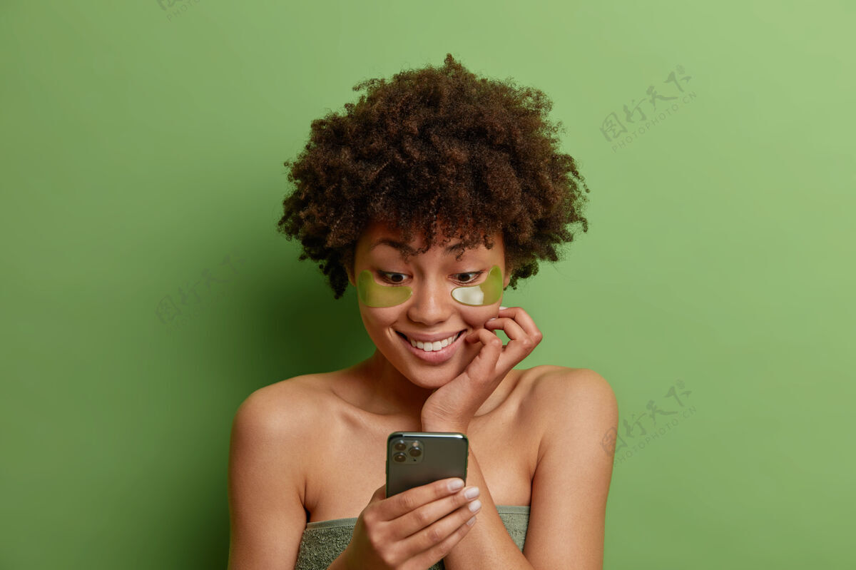 非洲图为卷发喜妇在眼部涂抹绿色保湿贴片进行美容绿色补丁皮肤