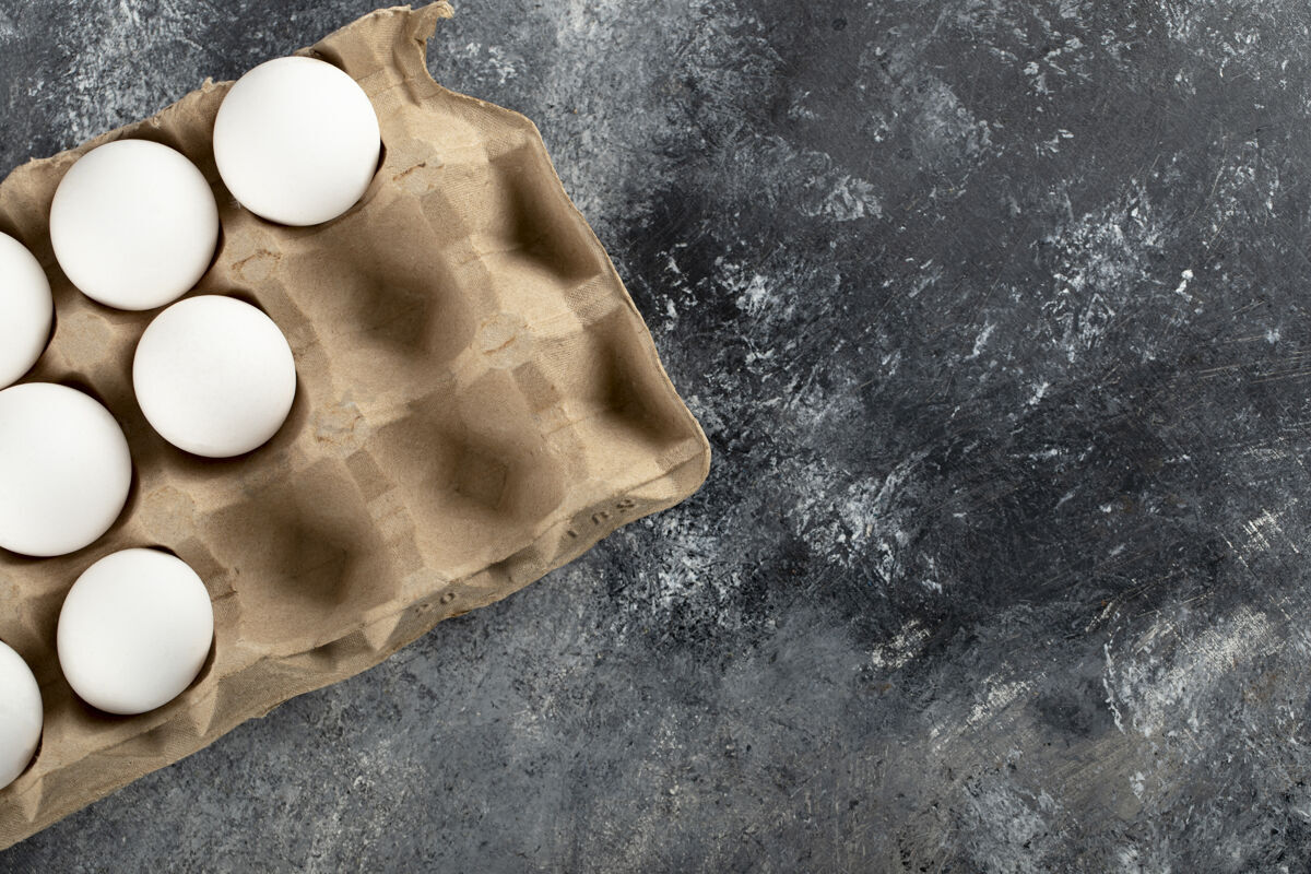 烹饪生鸡蛋放在大理石表面的鸡蛋盒里开放新鲜产品