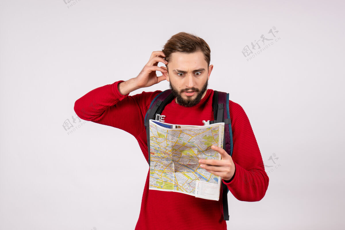成人正面图年轻男性游客带着背包在白色墙壁上探索地图科维德飞机度假情感病毒飞行色彩地图视图背包