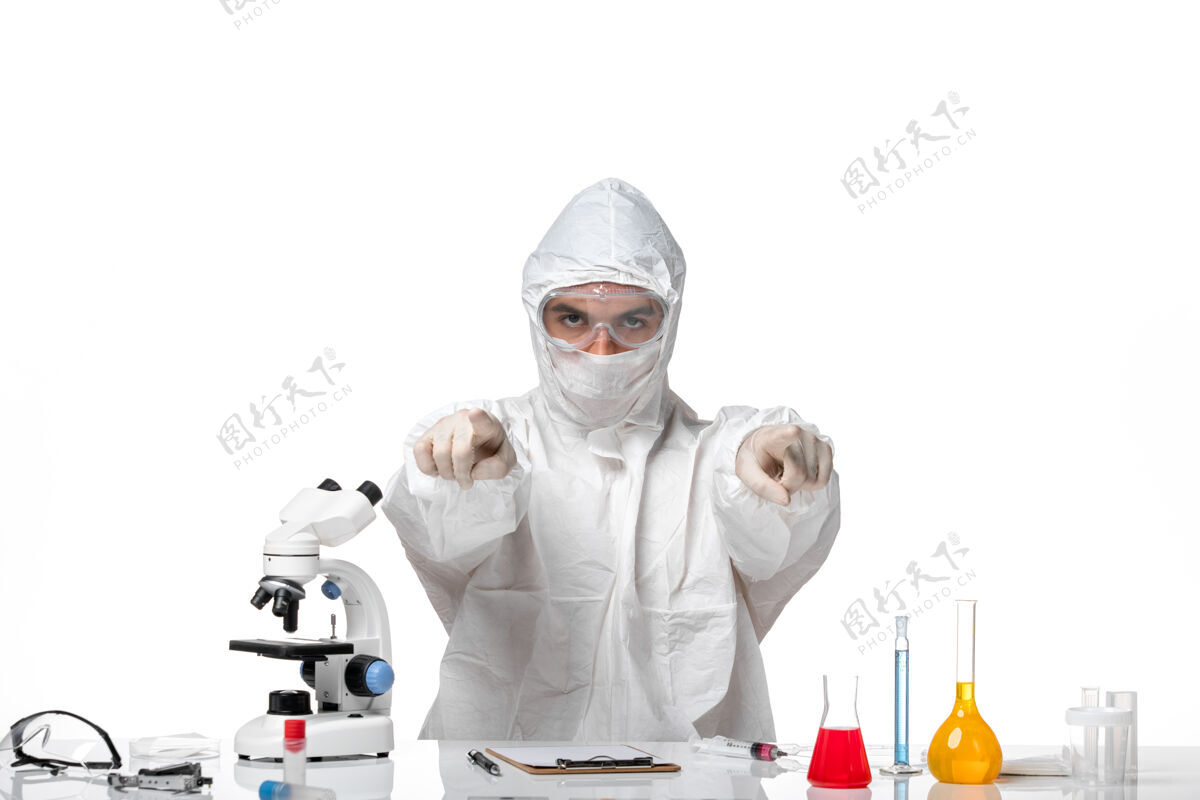 帽子正面图：男医生穿着防护服 戴着面具 因为科维德只是坐着 指着白色空间观点男医生化学