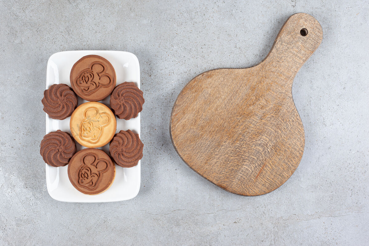 盘子一块木板和一盘饼干放在大理石背景上高质量的照片糕点糖填充