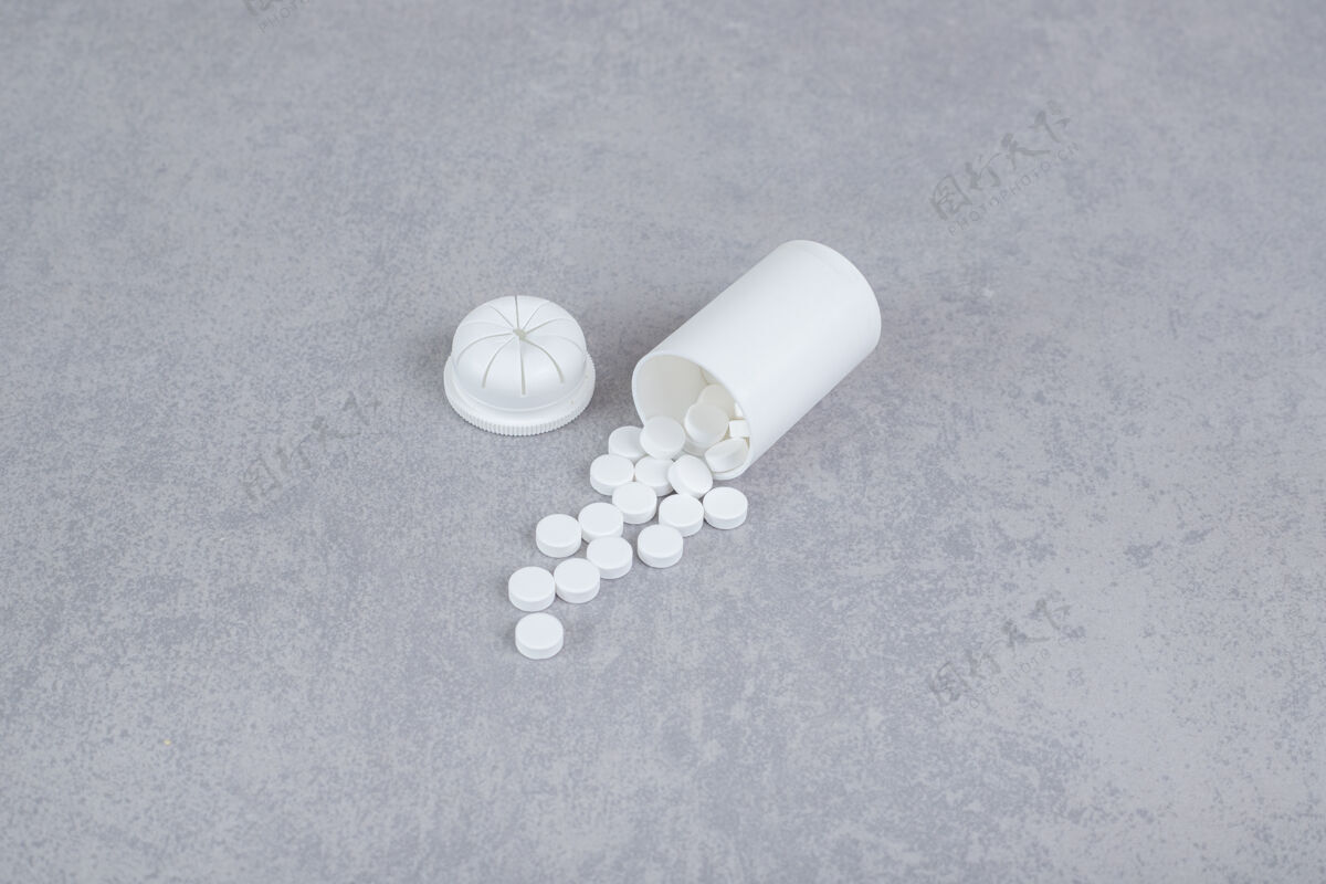 片剂灰色背景上的一小瓶白色药丸护理塑料药物
