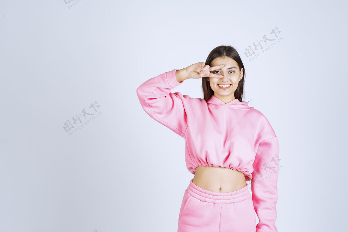 服装穿粉红色睡衣的女孩在手指间打量成人人类隐藏