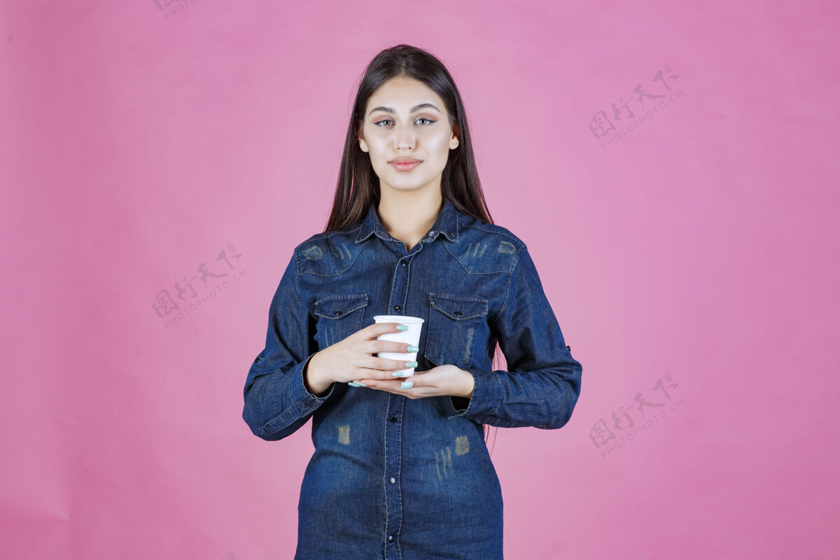 快乐穿着牛仔衬衫的女孩拿着咖啡杯 感觉很积极人女人女人