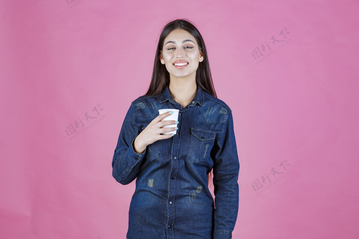 冬天穿着牛仔衬衫的女孩拿着咖啡杯 感觉很积极姿势女人装束
