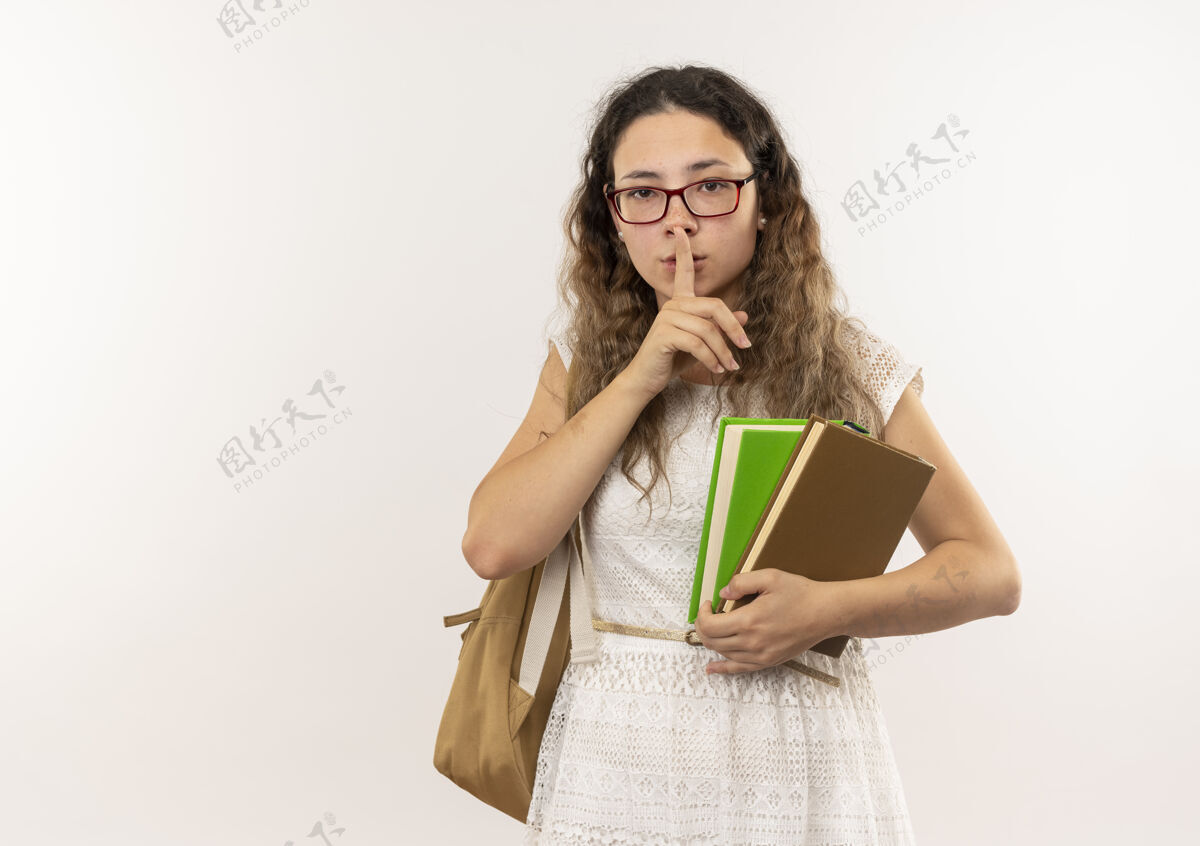 包年轻漂亮的女学生戴着眼镜 背着书包 拿着书 在白色的背景上安静地做着手势 还有复印空间女学生手势年轻