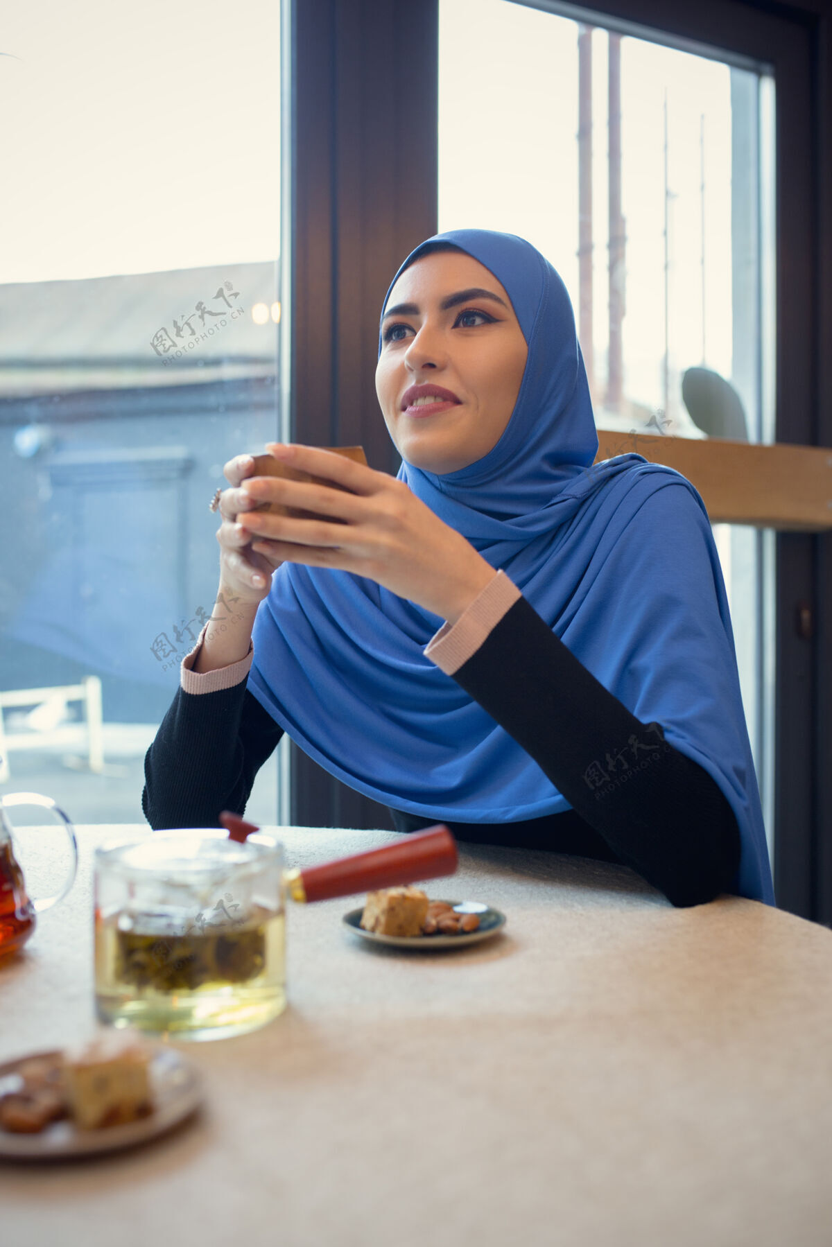 屏幕使用设备美丽的阿拉伯女人在咖啡馆或餐厅聚会 朋友或商务会议一起度过时光 交谈 欢笑穆斯林生活方式时尚快乐的化妆模特面部办公室化妆品