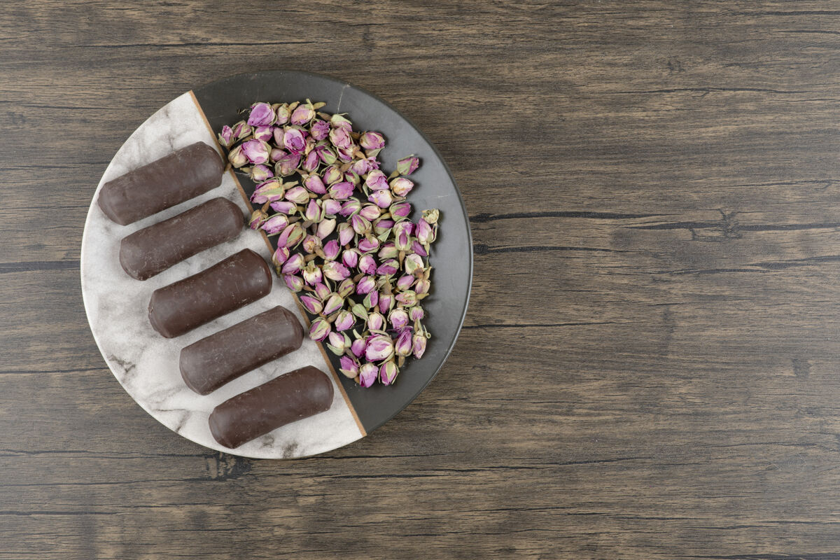 美食木桌上放着一盘巧克力奶油卷 奶油牛奶和玫瑰干美食蛋糕照片