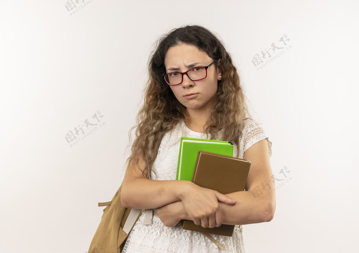 相机年轻漂亮的女学生戴着眼镜 背着书包 看着隔离在白色背景和复印空间的相机包不愉快背