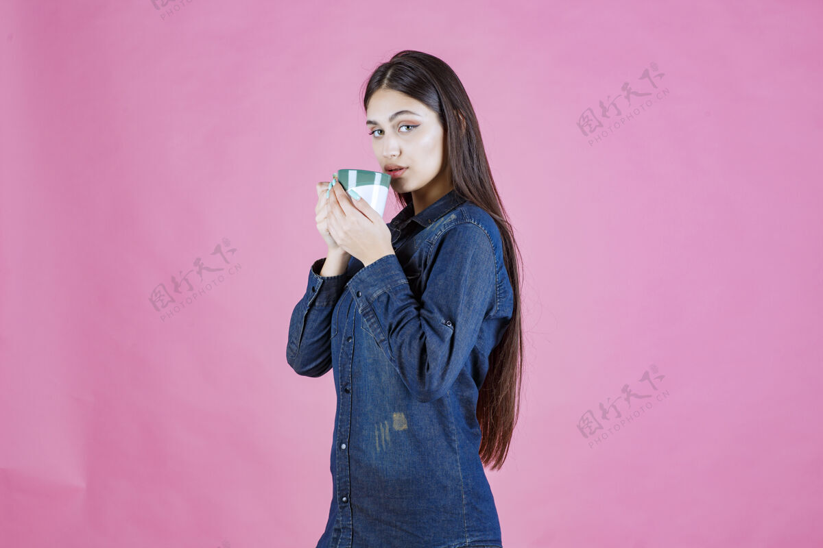 成人女孩拿着一个白绿色的咖啡杯 闻着姿势休闲商业