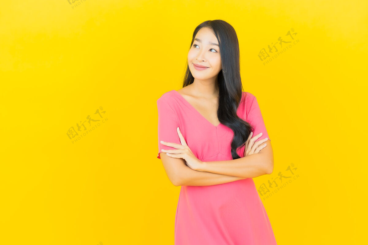 时髦黄色墙壁上 美丽的亚洲年轻女子身着粉色连衣裙微笑的画像亚洲人乐趣年轻