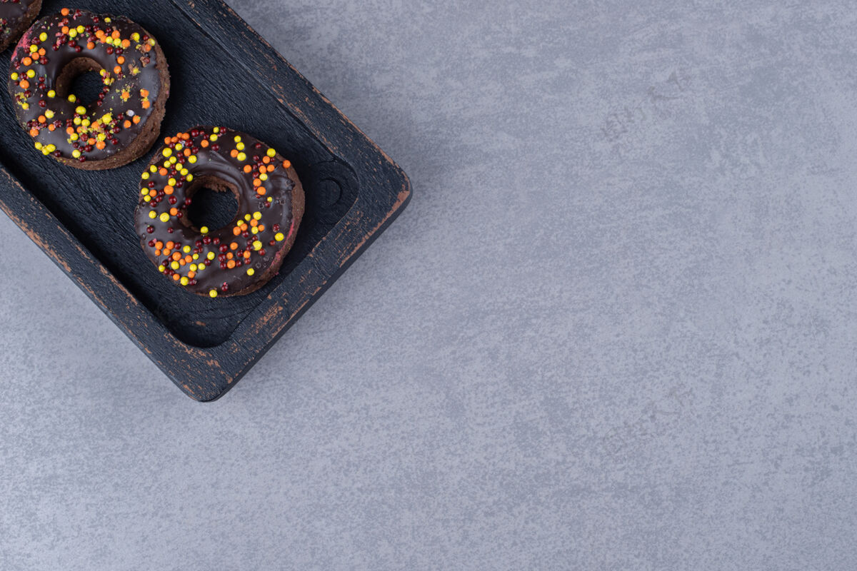 巧克力在大理石表面的盘子上放上巧克力和撒上糖果的甜甜圈烘焙食品美味美味
