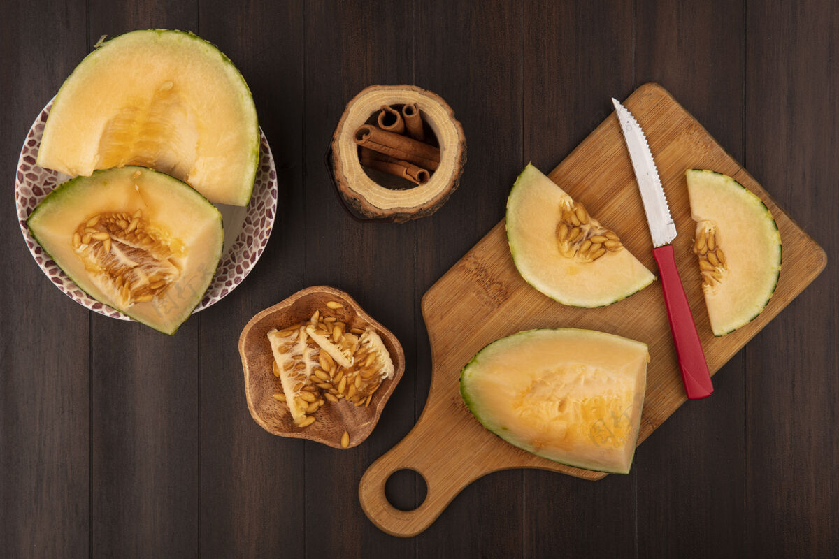 食品在木制的厨房板上 用刀和瓜子在木制的碗上 在木制的背景上 用肉桂棒 可以看到多汁甜甜的哈密瓜片的俯视图观点棒板