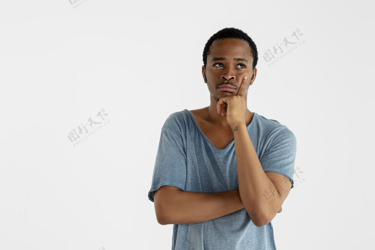 消极美丽的男性半身像孤立在白色的墙上年轻的情感非洲裔美国人在蓝色衬衫面部表情 人类的情感 广告概念思考 抬头看胡须微笑时尚