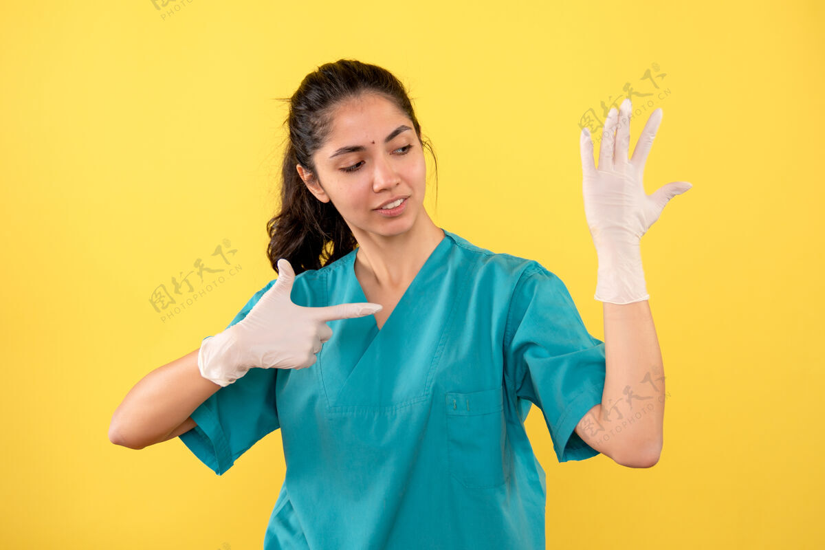 微笑前视图：戴着乳胶手套的女医生用手指指着她的手快乐女医生乳胶