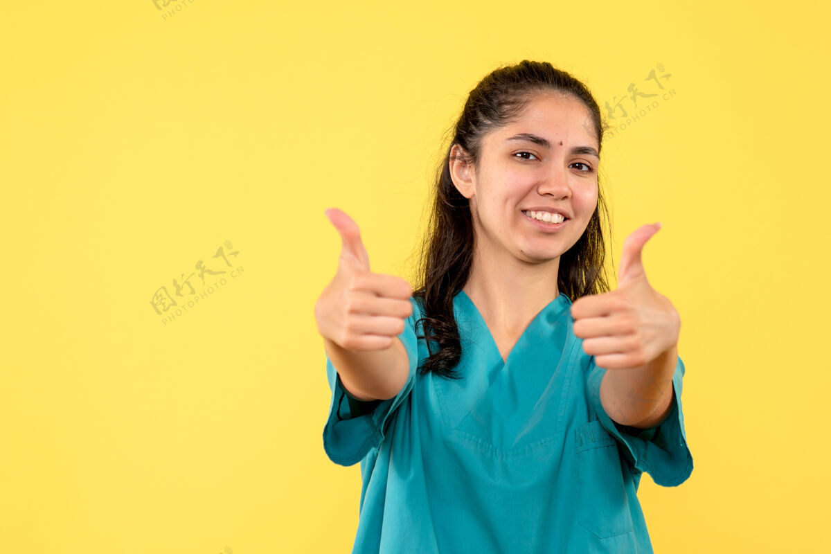 漂亮正面图穿着制服的女医生站着做拇指朝上的标志微笑成人人