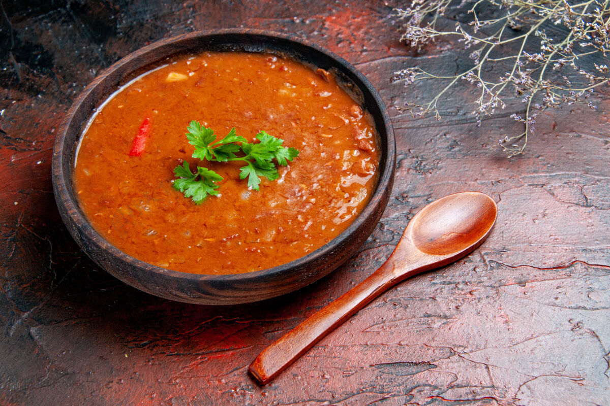 番茄汤在一个棕色的碗和调羹的混合颜色的桌子上的经典番茄汤的侧视图食物木勺汤