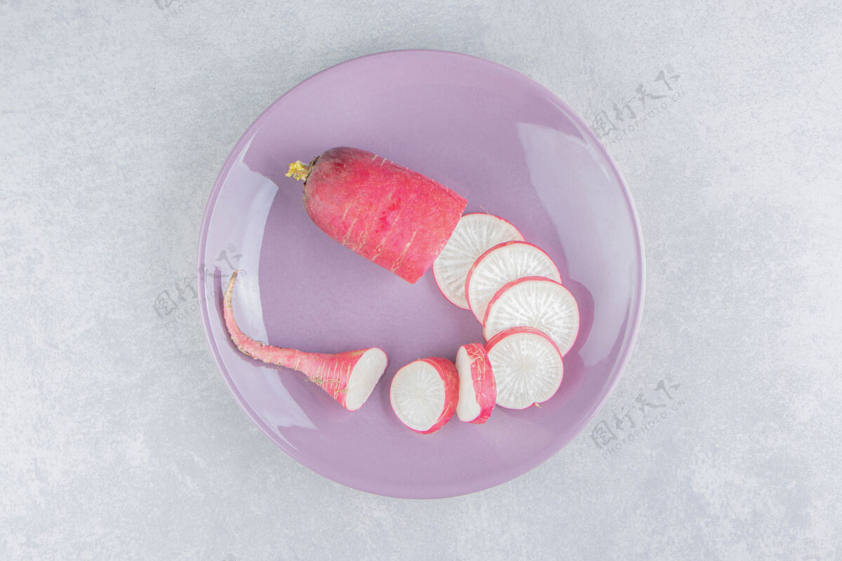 乡村成熟的萝卜片放在粉红色的盘子里 放在蓝色的表面上美味健康蔬菜