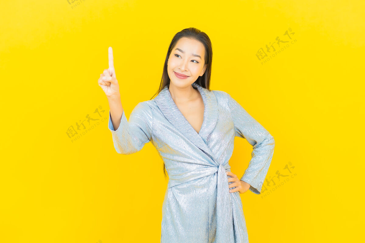 紫色在黄色的墙上描绘美丽的亚洲年轻女子微笑着行动女人欢呼中国人