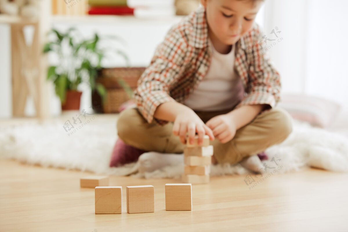 可爱坐在地板上的小孩漂亮的男孩在家里玩木制立方体概念图像与复制或负空间和模拟你的文字砖块男孩人