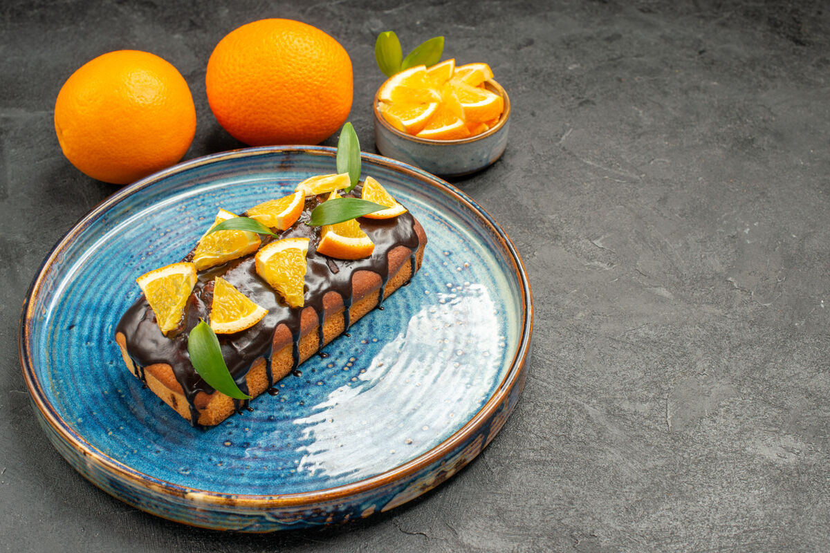 食品托盘上柔软美味的蛋糕和黑桌子上柠檬的水平视图横柑橘盘子