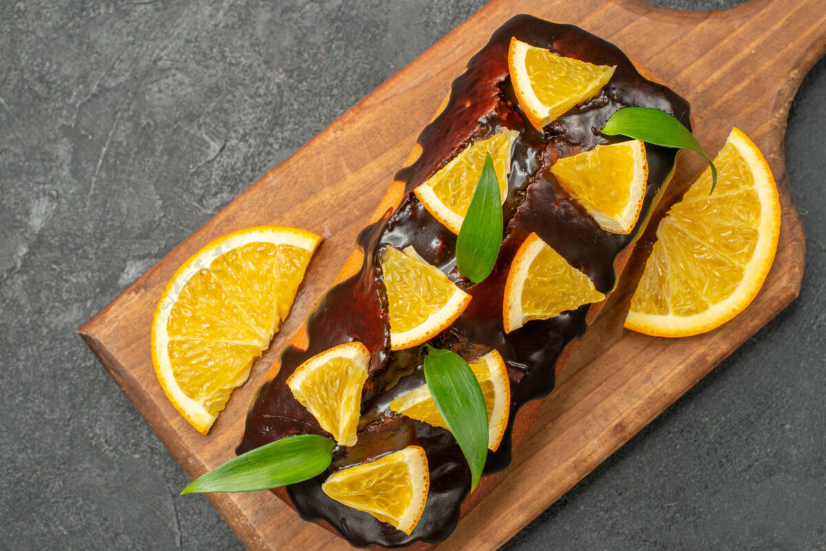 装饰特写镜头美味的蛋糕装饰与橙色和巧克力在砧板上的黑表水果盘子餐厅