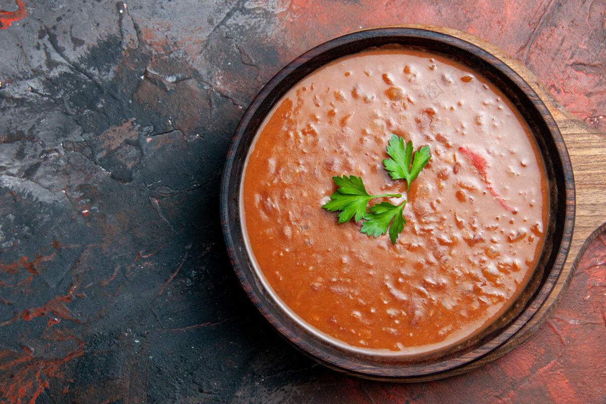 新鲜番茄汤放在一个棕色的砧板上 在一张五颜六色的桌子的右边晚餐餐厅食宿