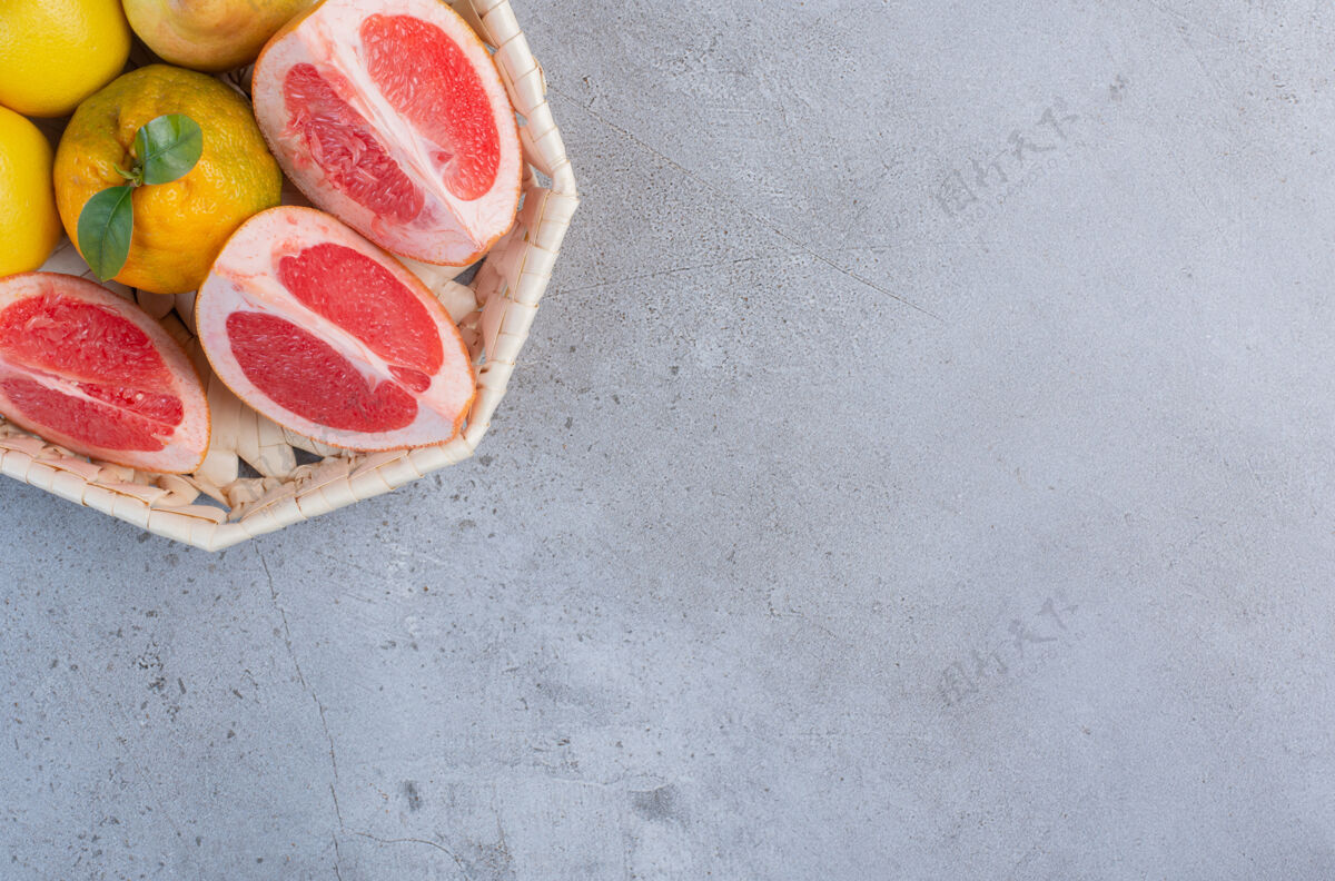 美味雪梨和葡萄柚片放在大理石背景上的白色篮子里美味柚子风味