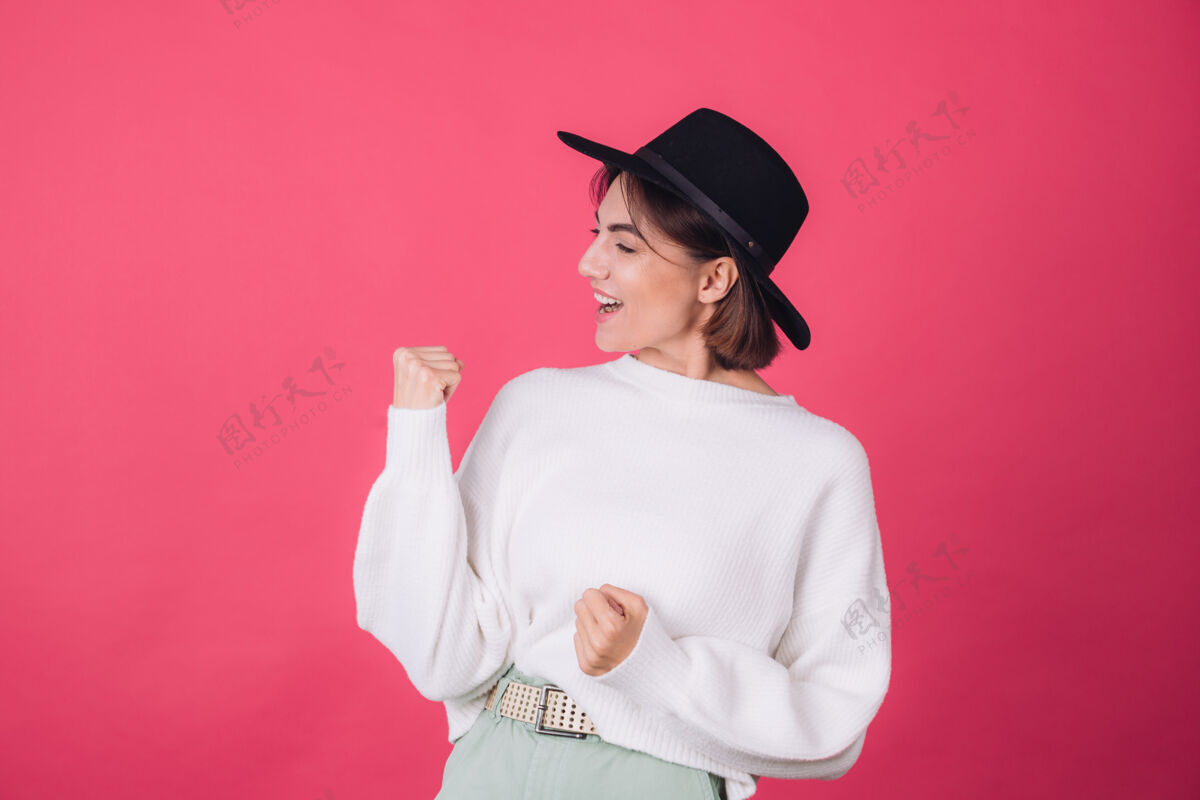 脸穿着白色休闲毛衣 戴着红粉色帽子的时髦女人快乐展示自然