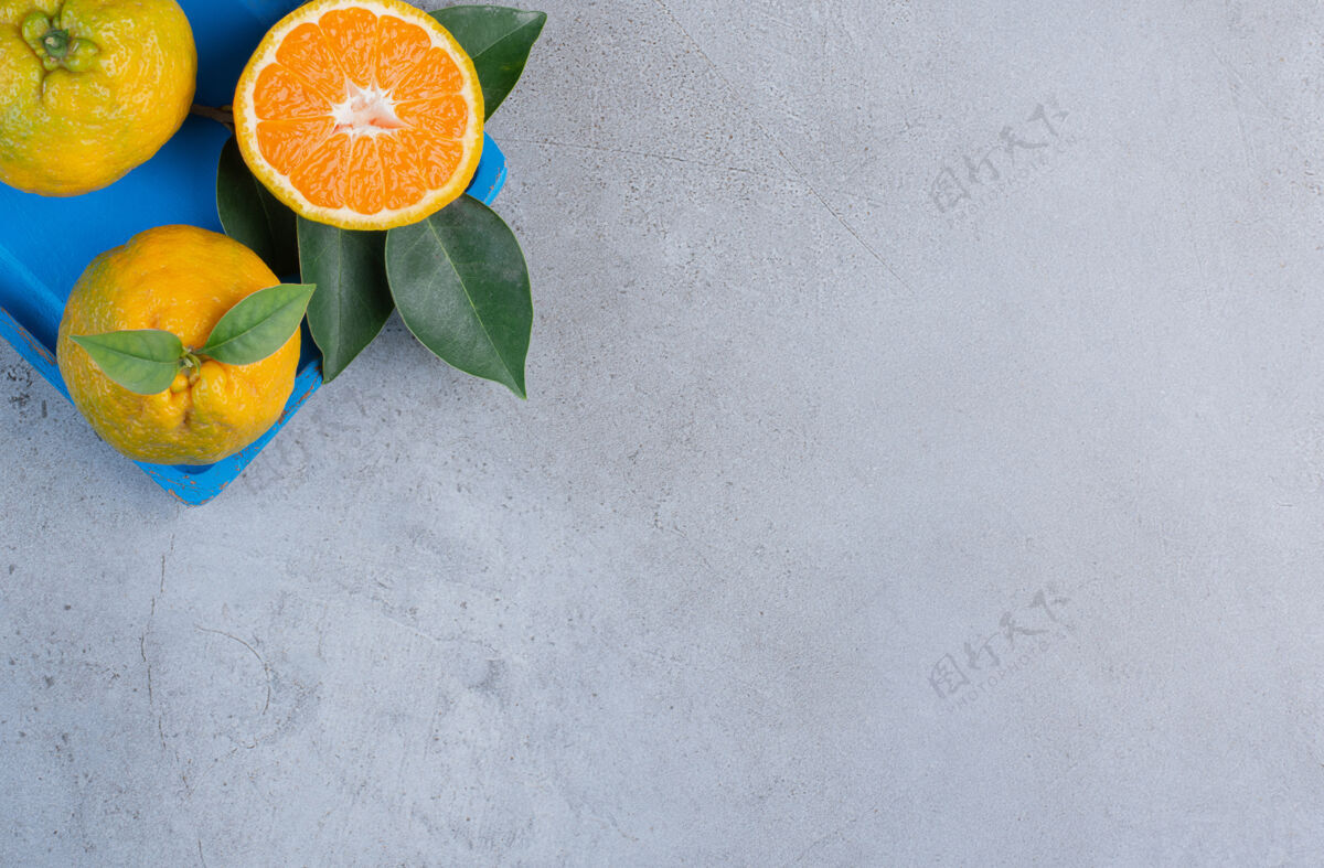 营养橘子和叶子放在一个蓝色的小盘子里 背景是大理石美味柑橘风味