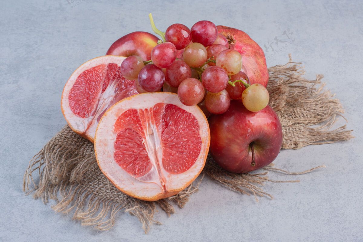 特写新鲜的有机水果苹果 葡萄和橘子的灰色背景美味篮子堆