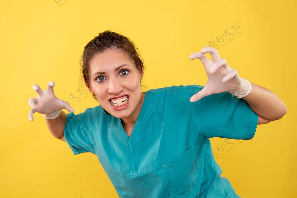 病毒正面图黄色背景上戴着医用手套的女医生摆出野性姿势健康成人视图