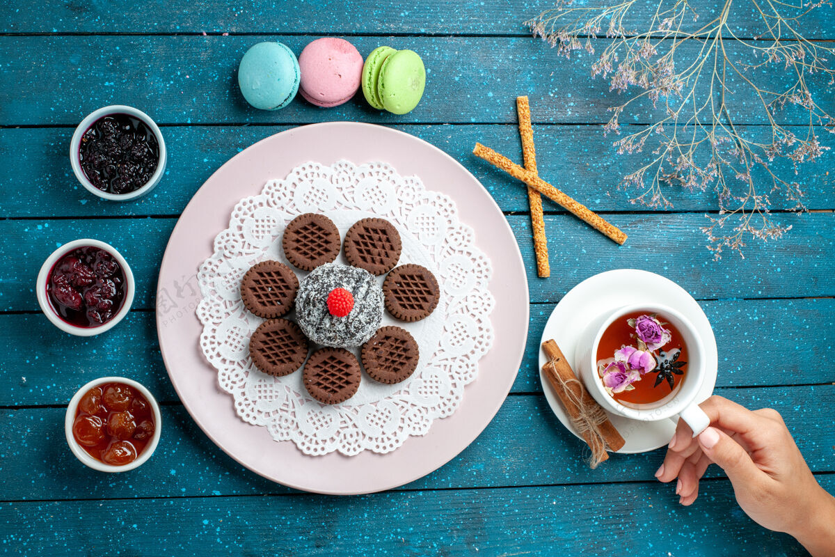 乡村俯瞰美味的巧克力饼干加果酱和一杯茶放在蓝色的乡村办公桌上饼干茶饼干甜甜的蛋糕糖瓷器盘子容器