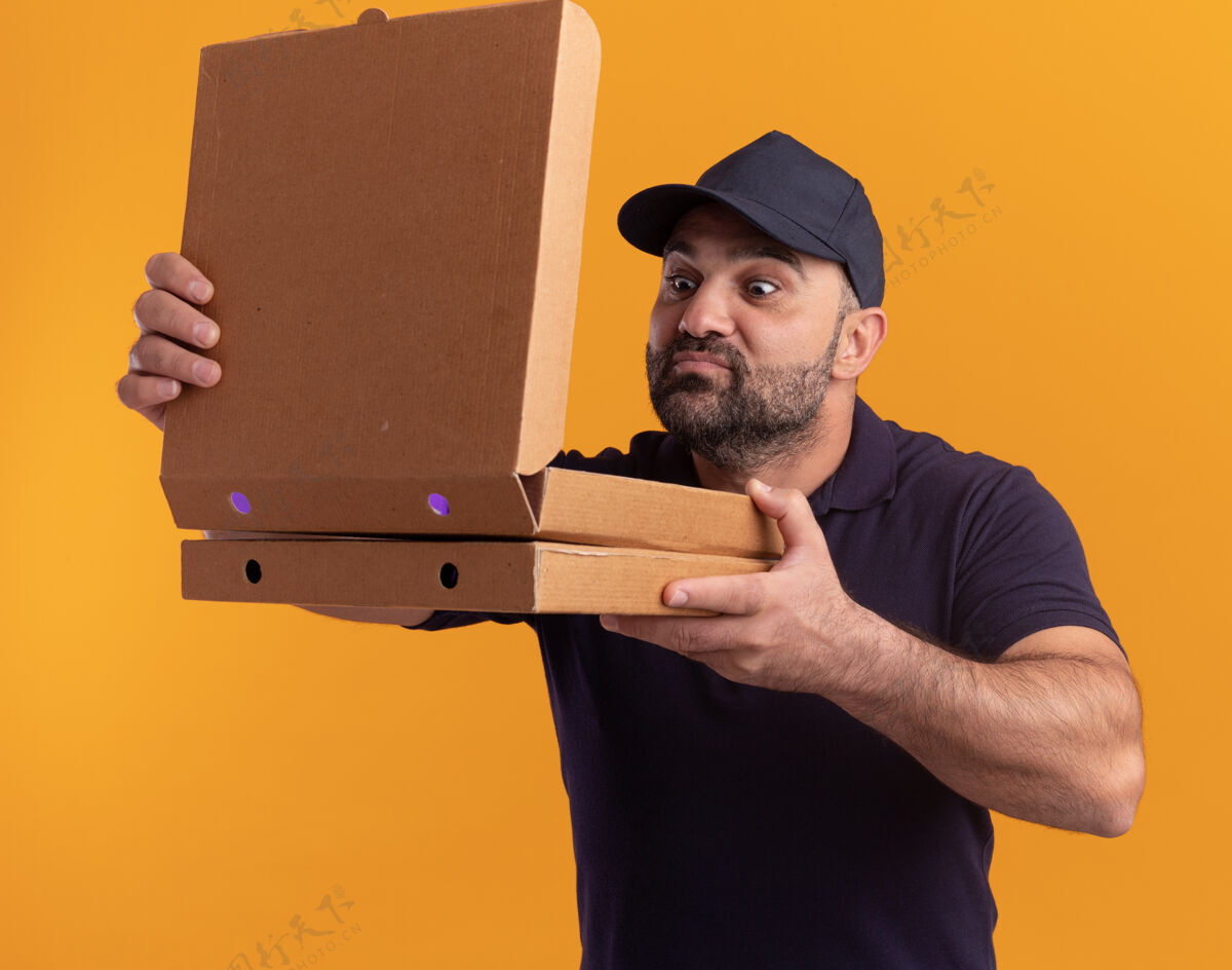 请身着制服的中年送货员高兴地打开瓶盖 嗅着隔离在黄色墙上的披萨盒送货制服盒子