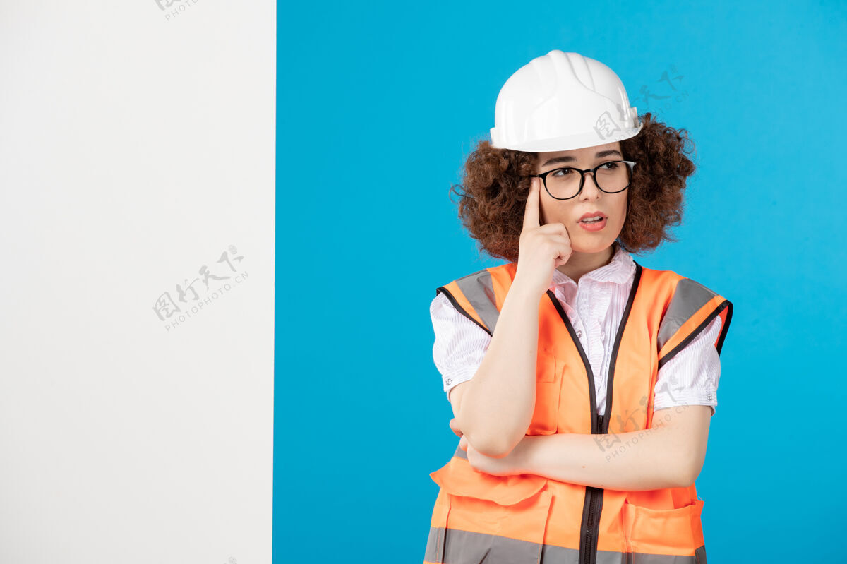 前面前视图蓝色墙上穿着制服的女建筑工人背心专业工作