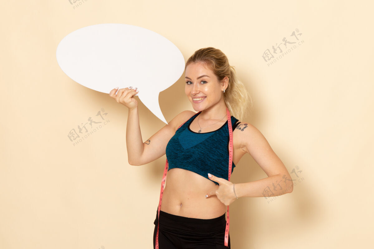 漂亮正面图身穿运动装的年轻女性手持白色标志微笑着服装比基尼腹部