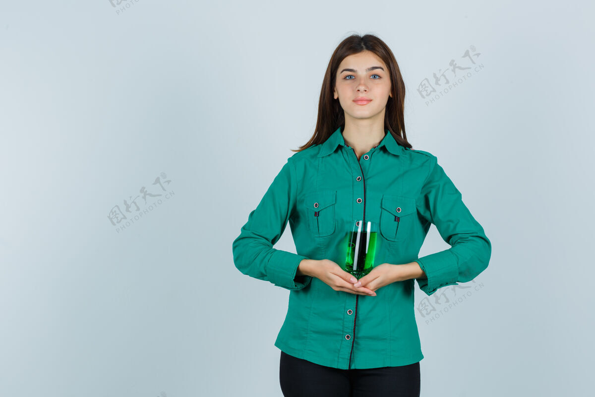 女人年轻女孩手拿一杯绿色液体 穿着绿色上衣 黑色裤子 看上去很欢快 正面照肖像人时尚