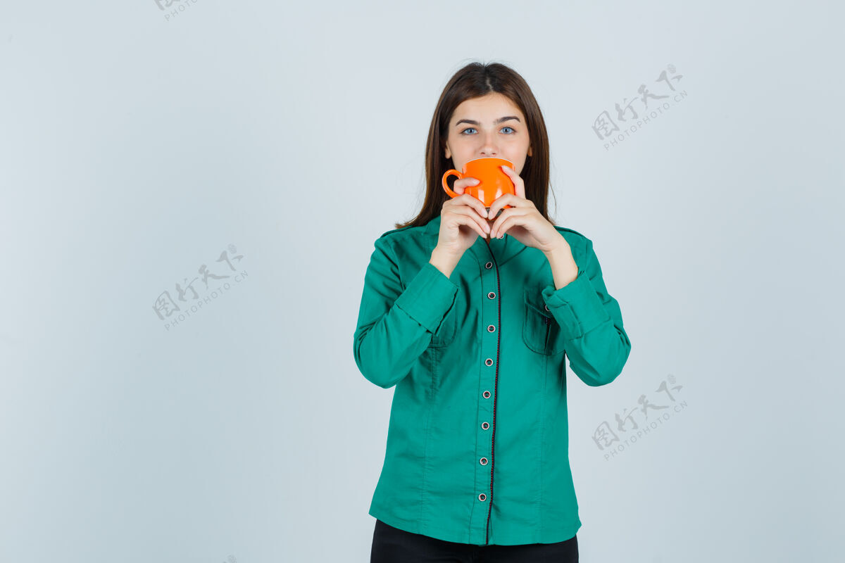 头发年轻的女士穿着衬衫 喝着橘色茶杯里的茶 看上去很自信正面图人肖像时尚